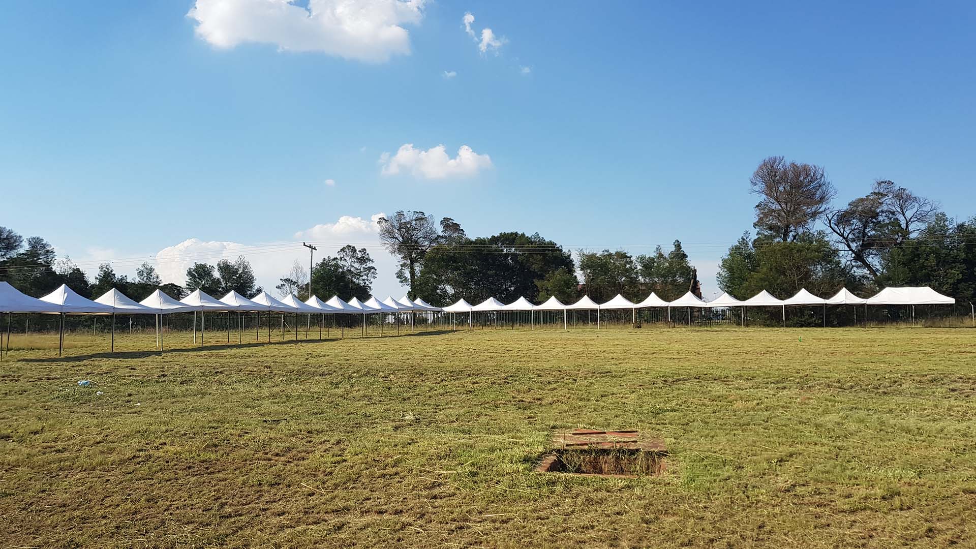 Row of white pop-up gazebos set up on an open field.
