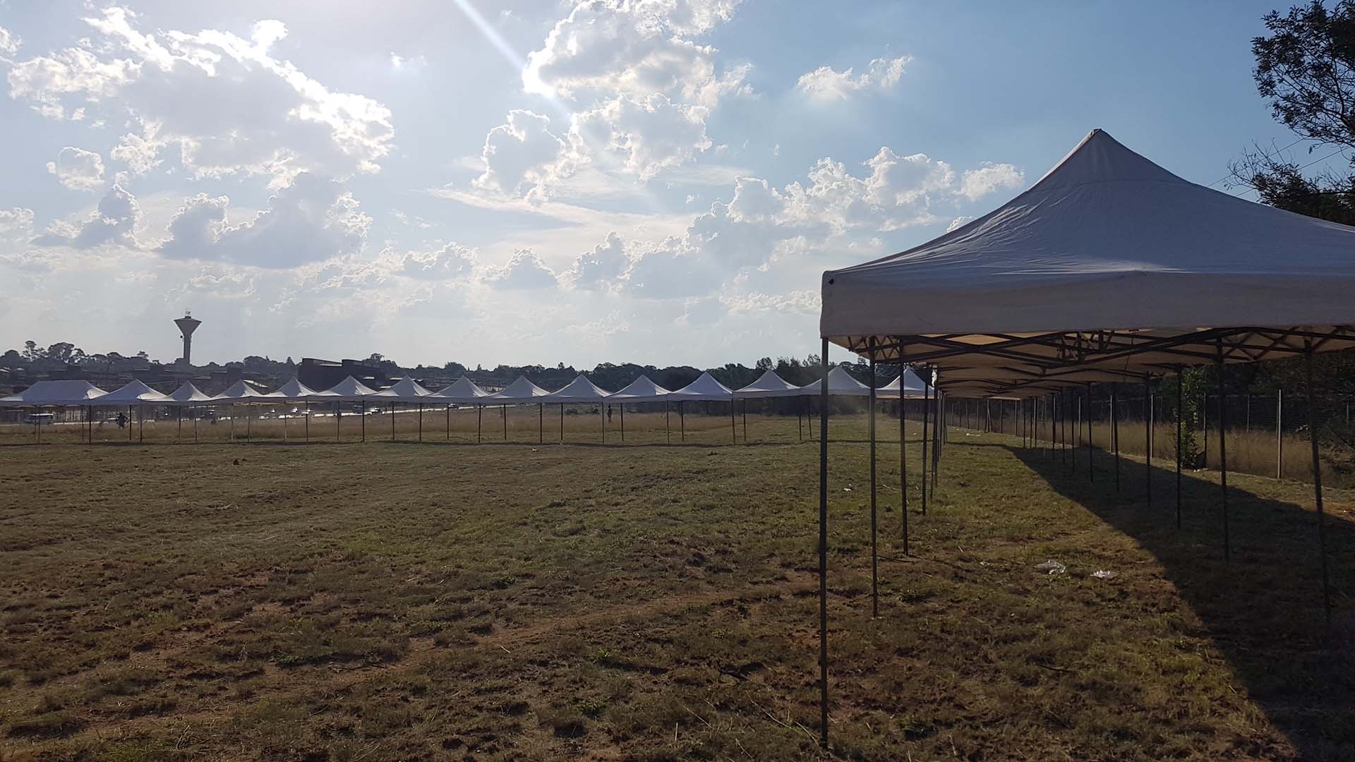 Row of white pop-up gazebos in a grassy field