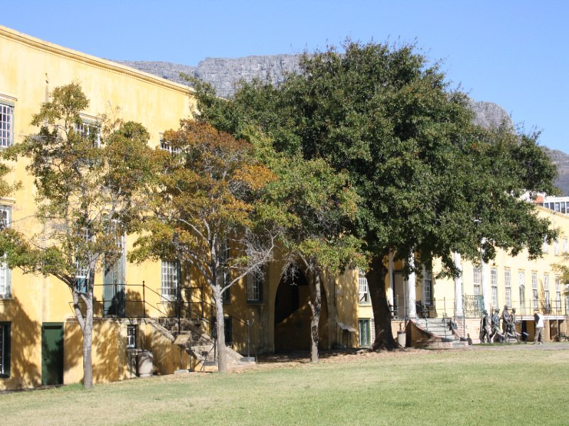 Lush garden area at the Castle of Good Hope with trees and historic buildings