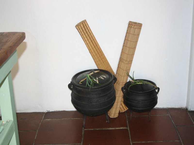 Two black pots and woven mats in a historic setting