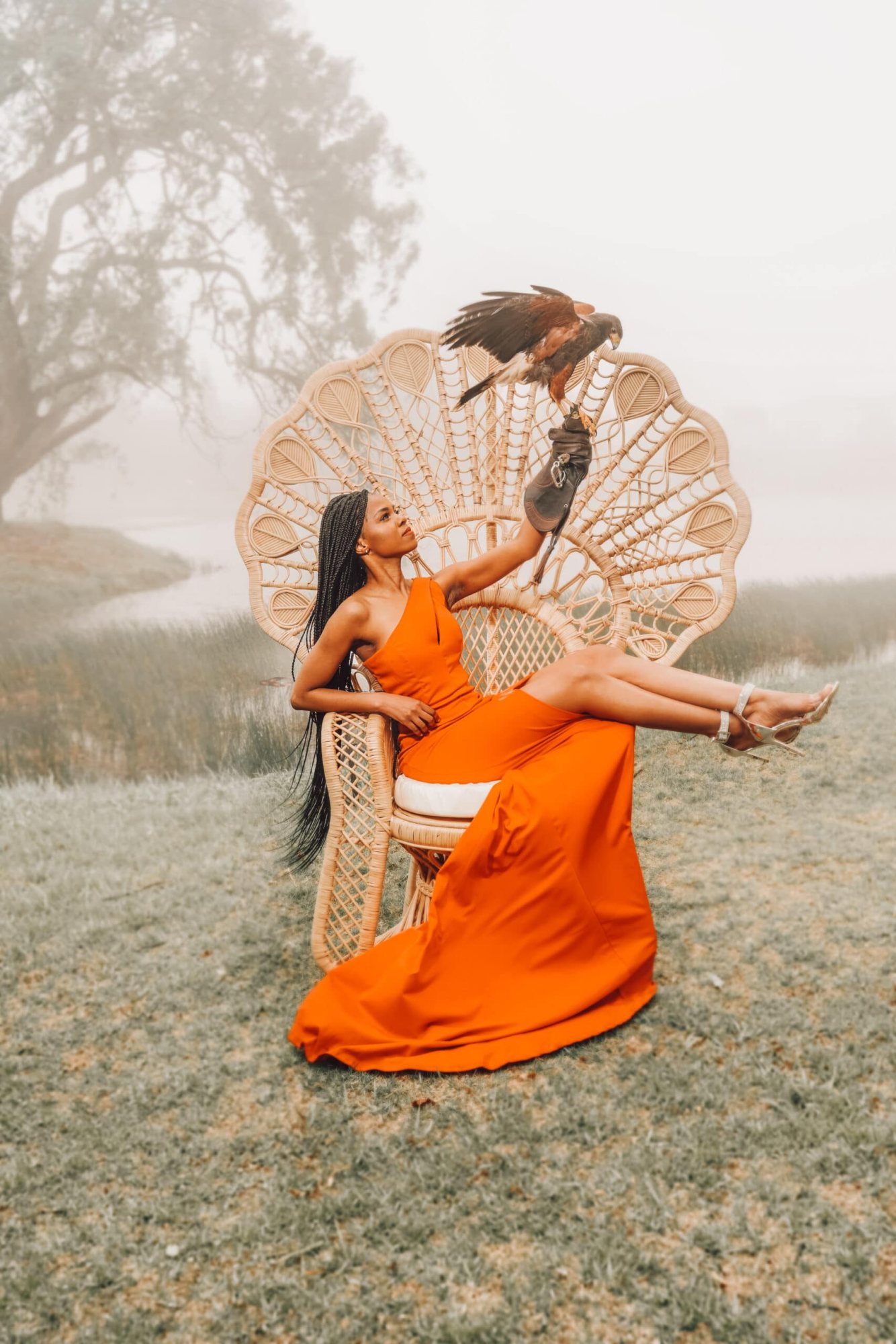 Woman in orange dress seated on Peacock Pose Emperor Chair