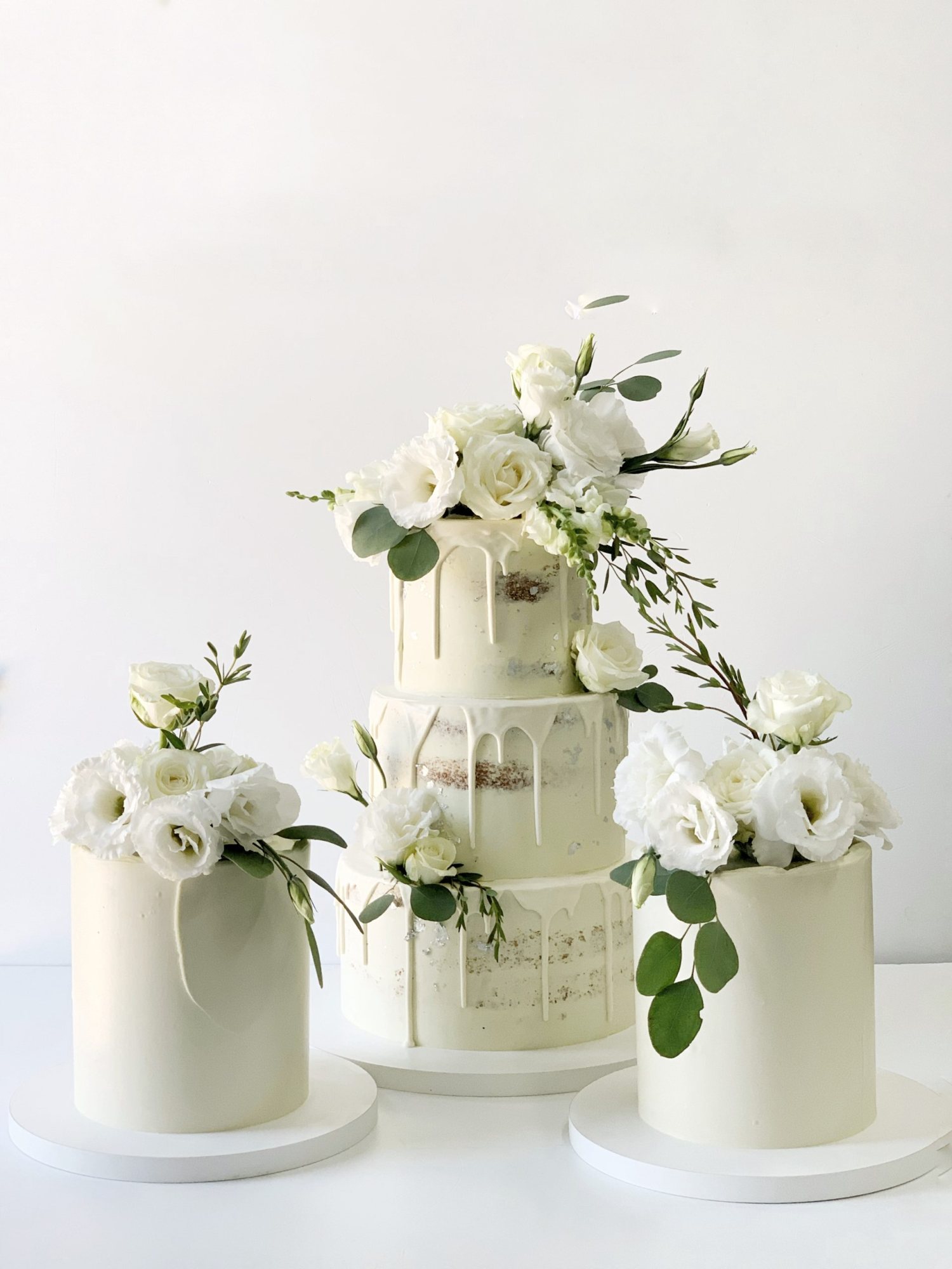 Three white decorative cakes with fresh flowers