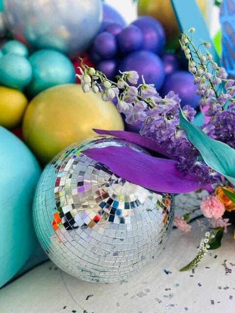 Colorful party décor with a disco ball and floral accents