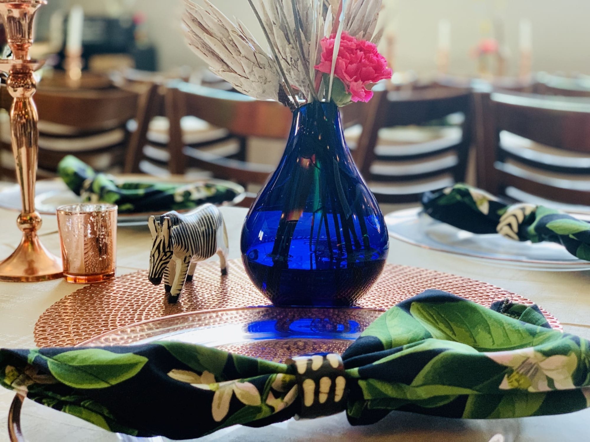 Table setting with blue vase, floral decor, and zebra figurine.