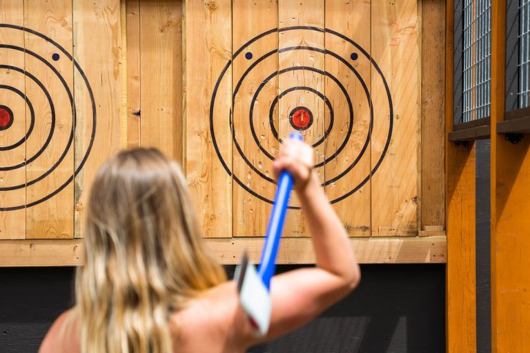 Person throwing an axe at a target with concentric circles.