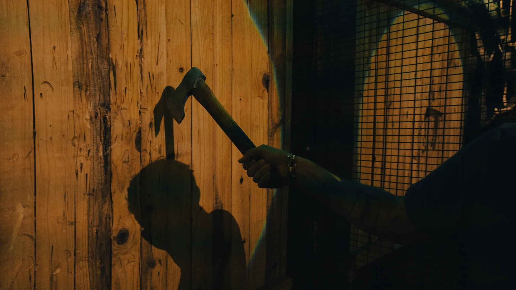 Axe held above a wooden target with a shadow