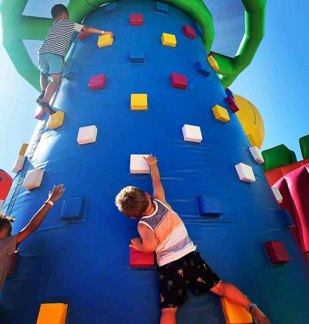 Children climbing an inflatable wall with colorful holds
