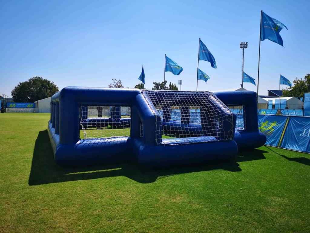 Inflatable soccer field with goals and nets on a grassy field.