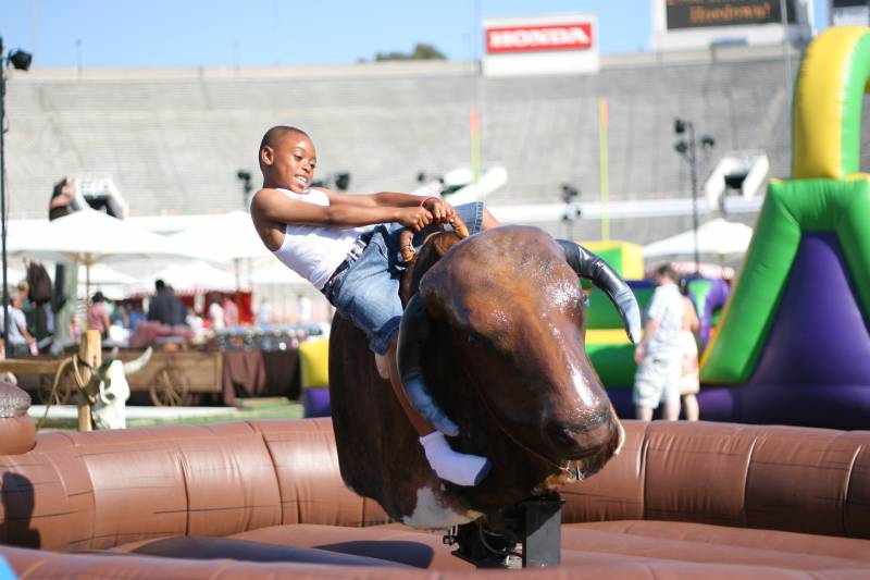 Child riding a mechanical bull at an outdoor event