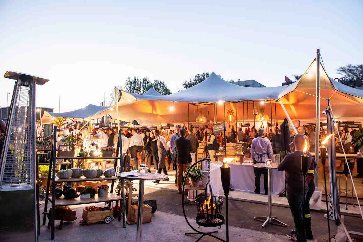 Outdoor event with tents and vendor displays in the evening