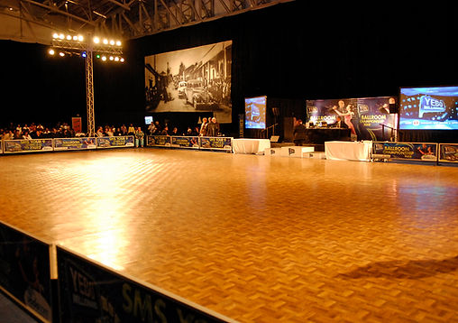 Wooden dance floor with banners and a large crowd in the background