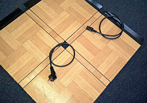 Close-up of an interlocking dance floor section with power cables.