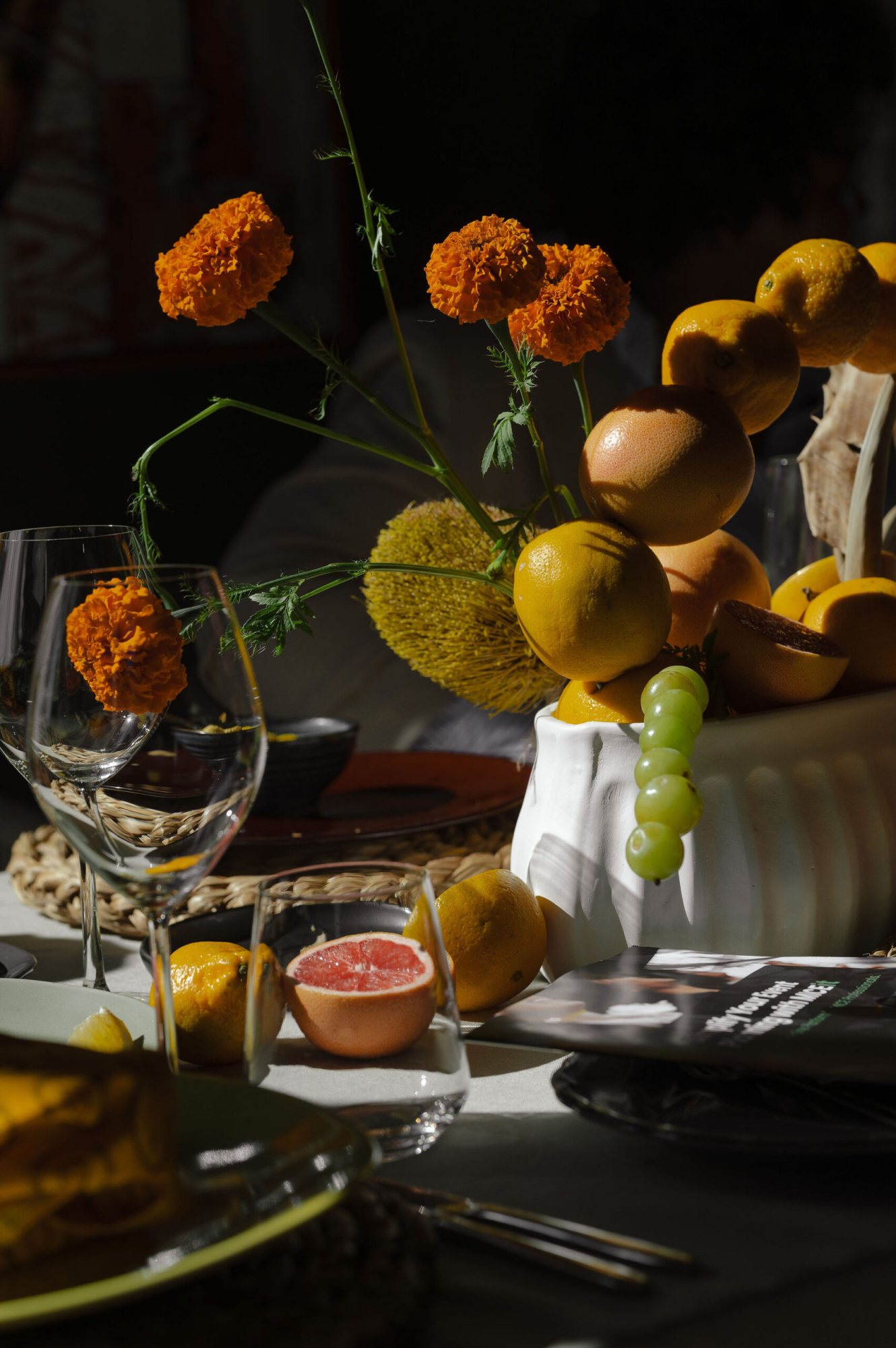 Arrangement of citrus fruits and marigolds on a table.