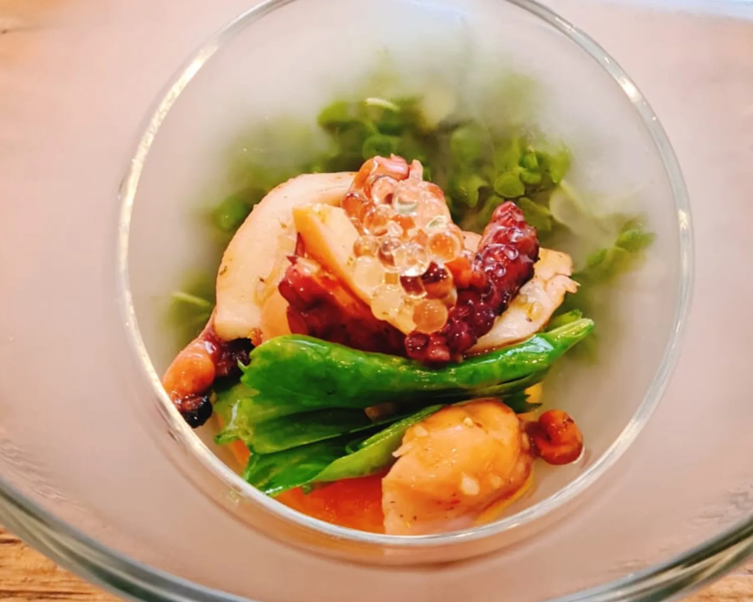 Gourmet seafood dish with greens in a glass bowl