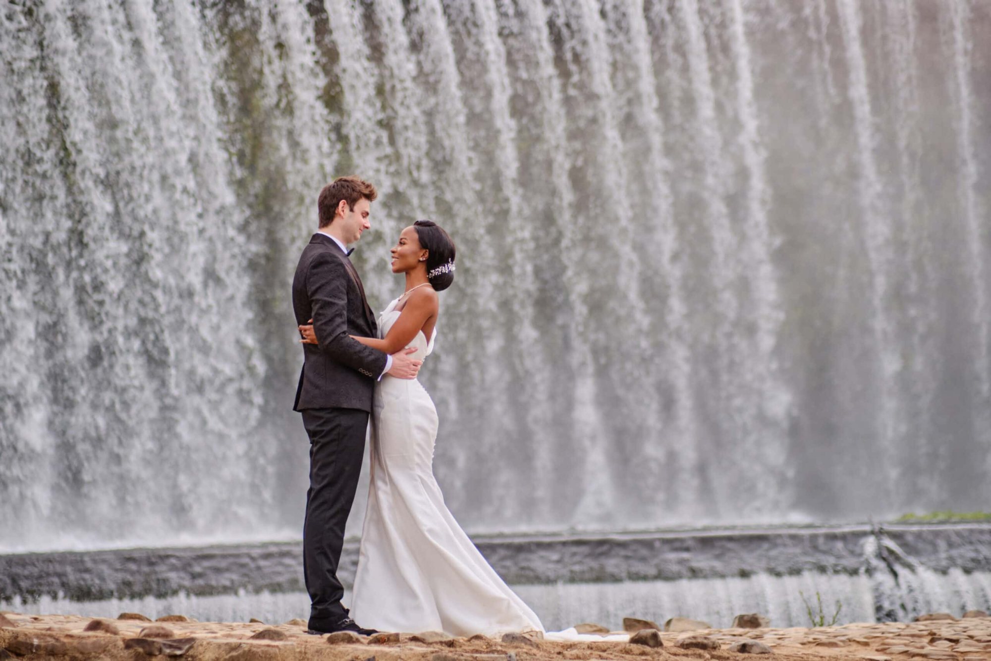 Bride and groom standing by a waterfall