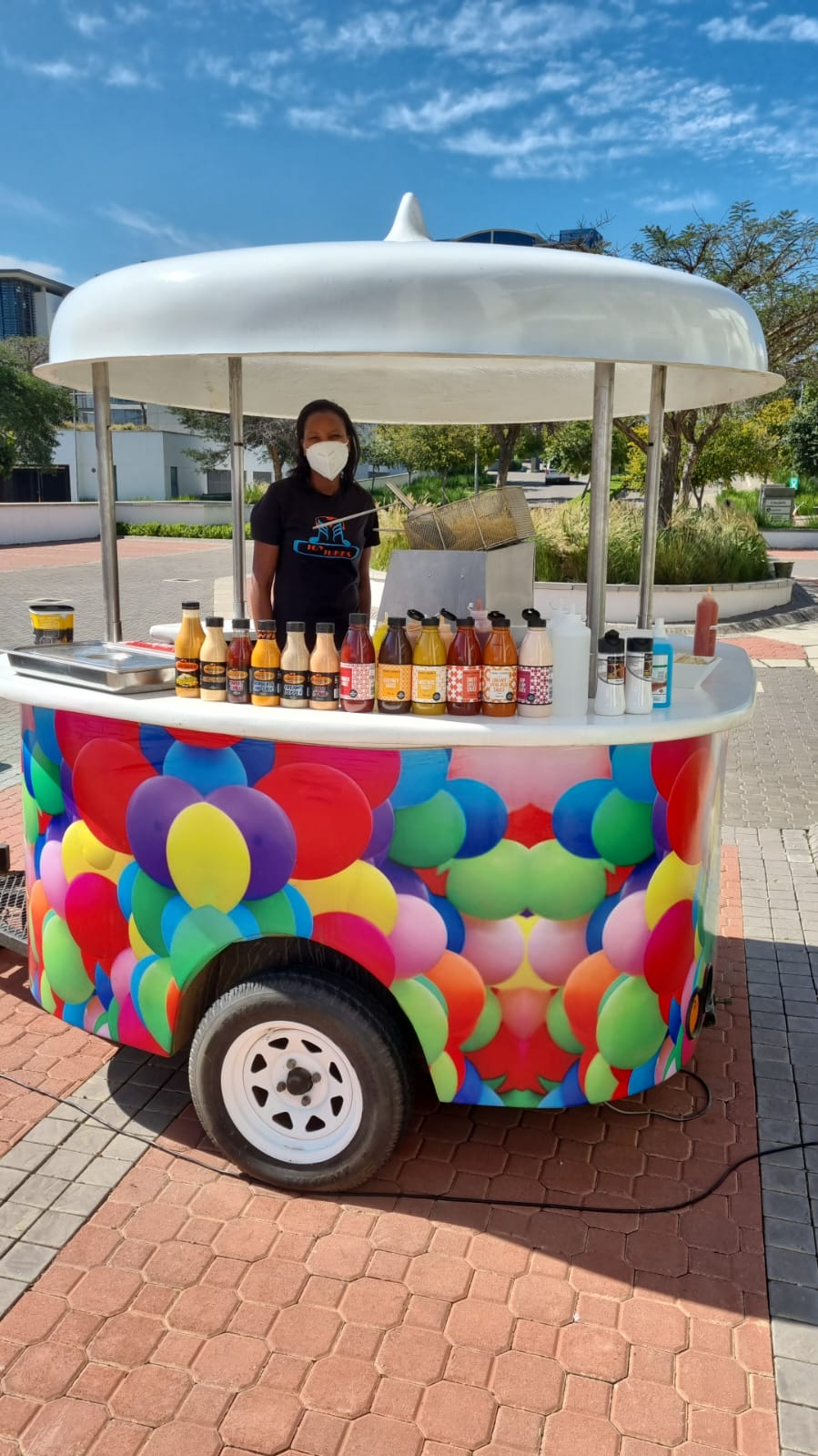 Vibrant snack cart with beverage bottles and vendor.
