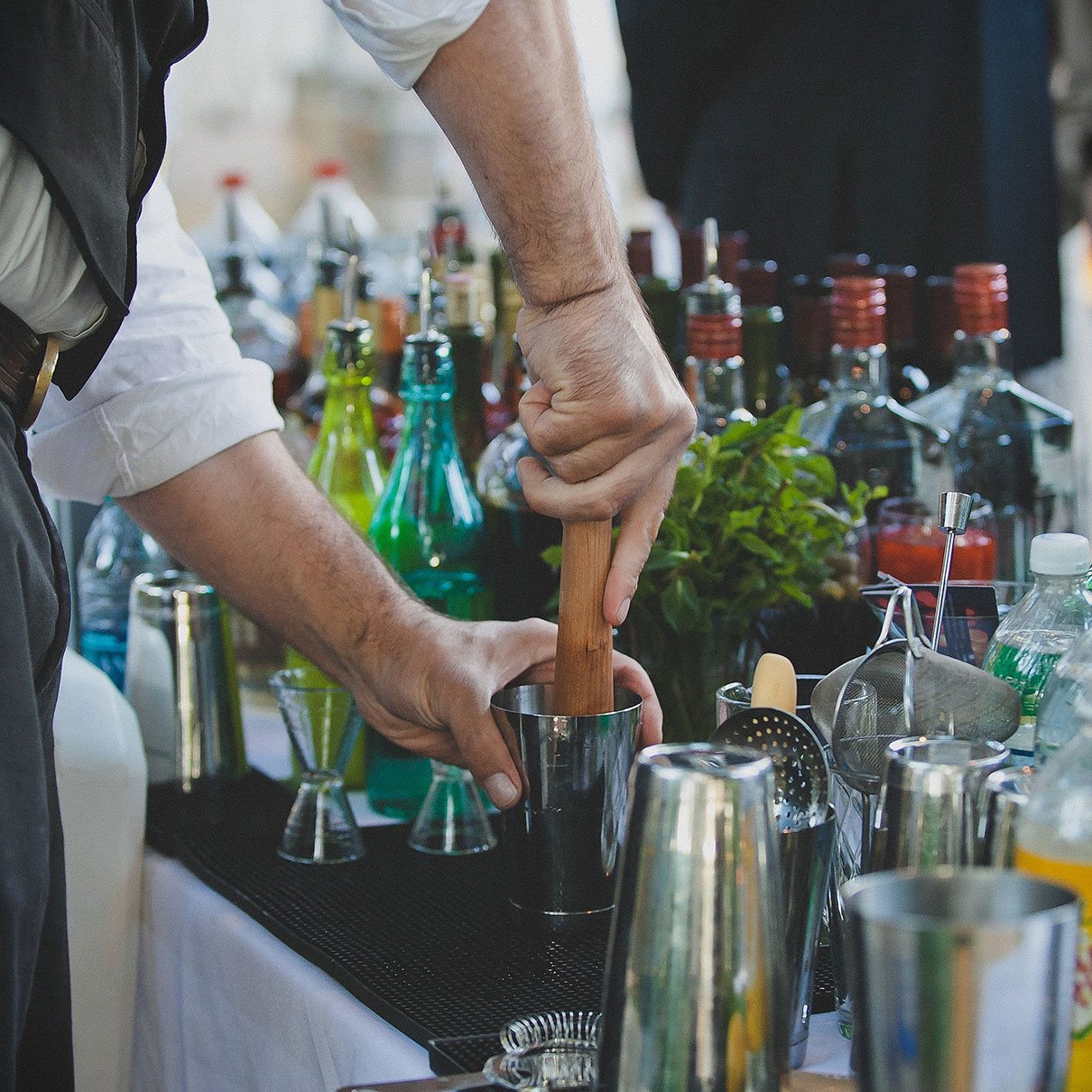 Bartender mixing cocktails with colorful bottles in the background
