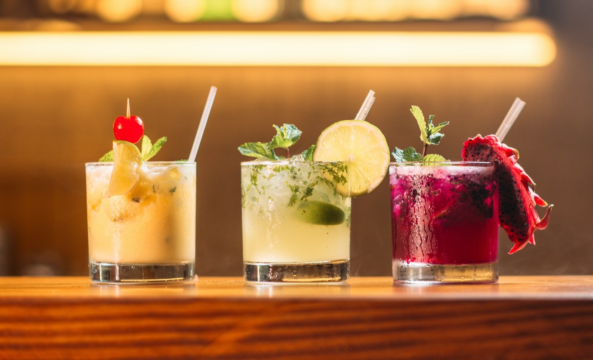 Three cocktails in clear glasses with fresh garnishes