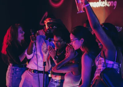 Group of friends singing karaoke with drinks