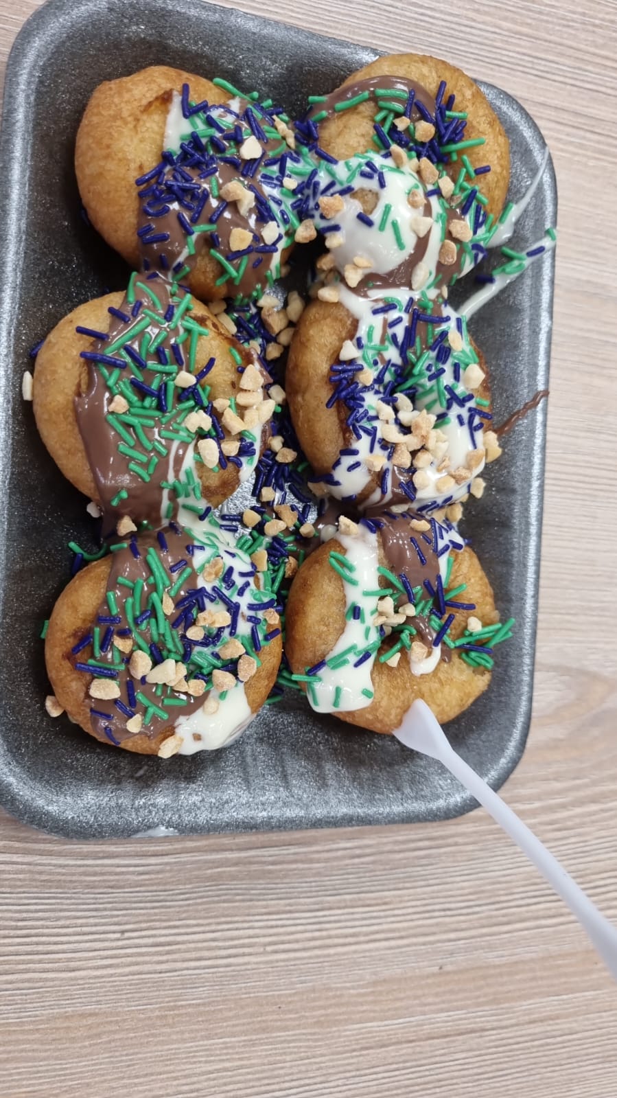 A tray of decorated party treats with chocolate and sprinkles