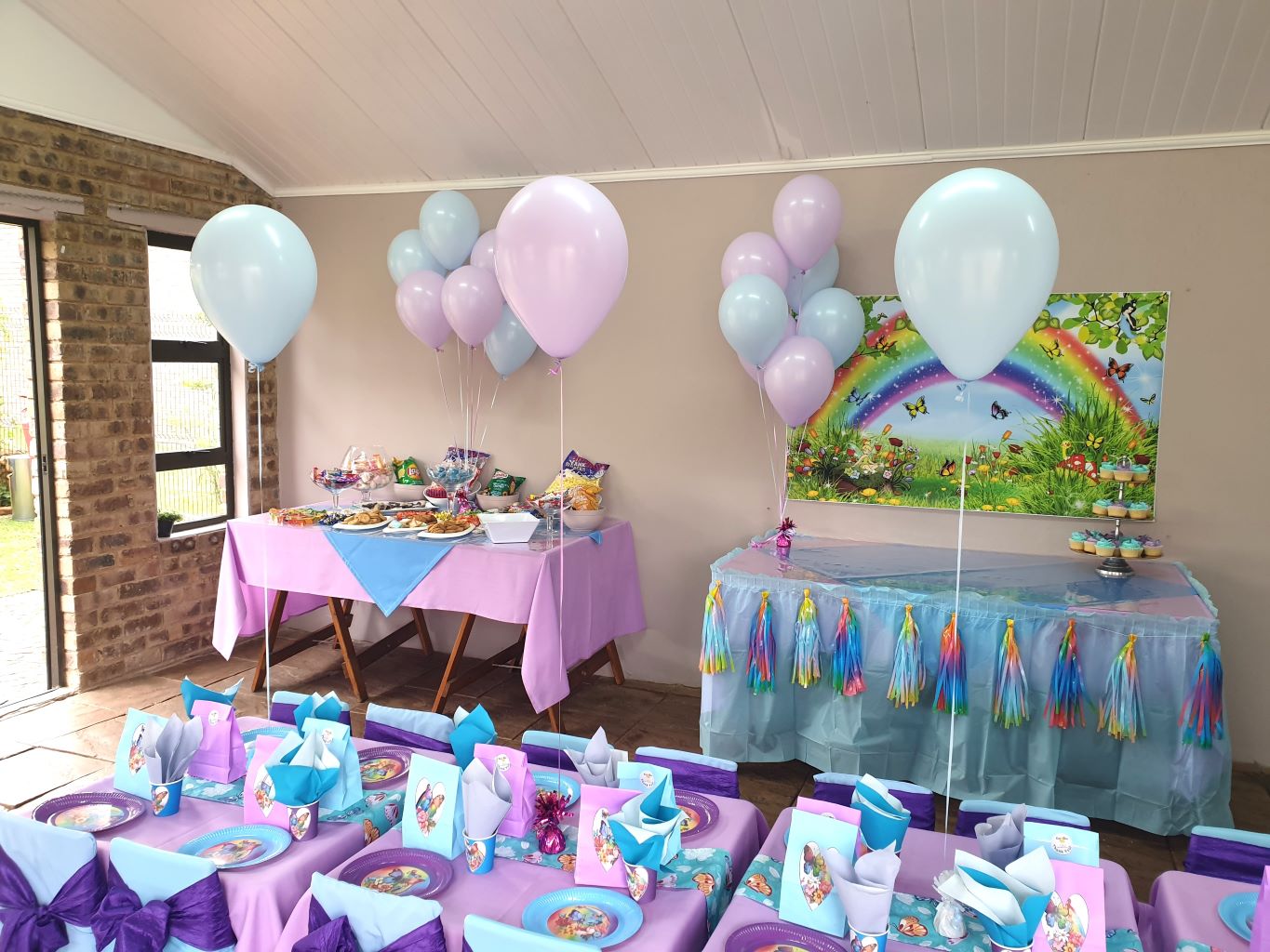 Colorful party setup with tables, balloons, and decorations.