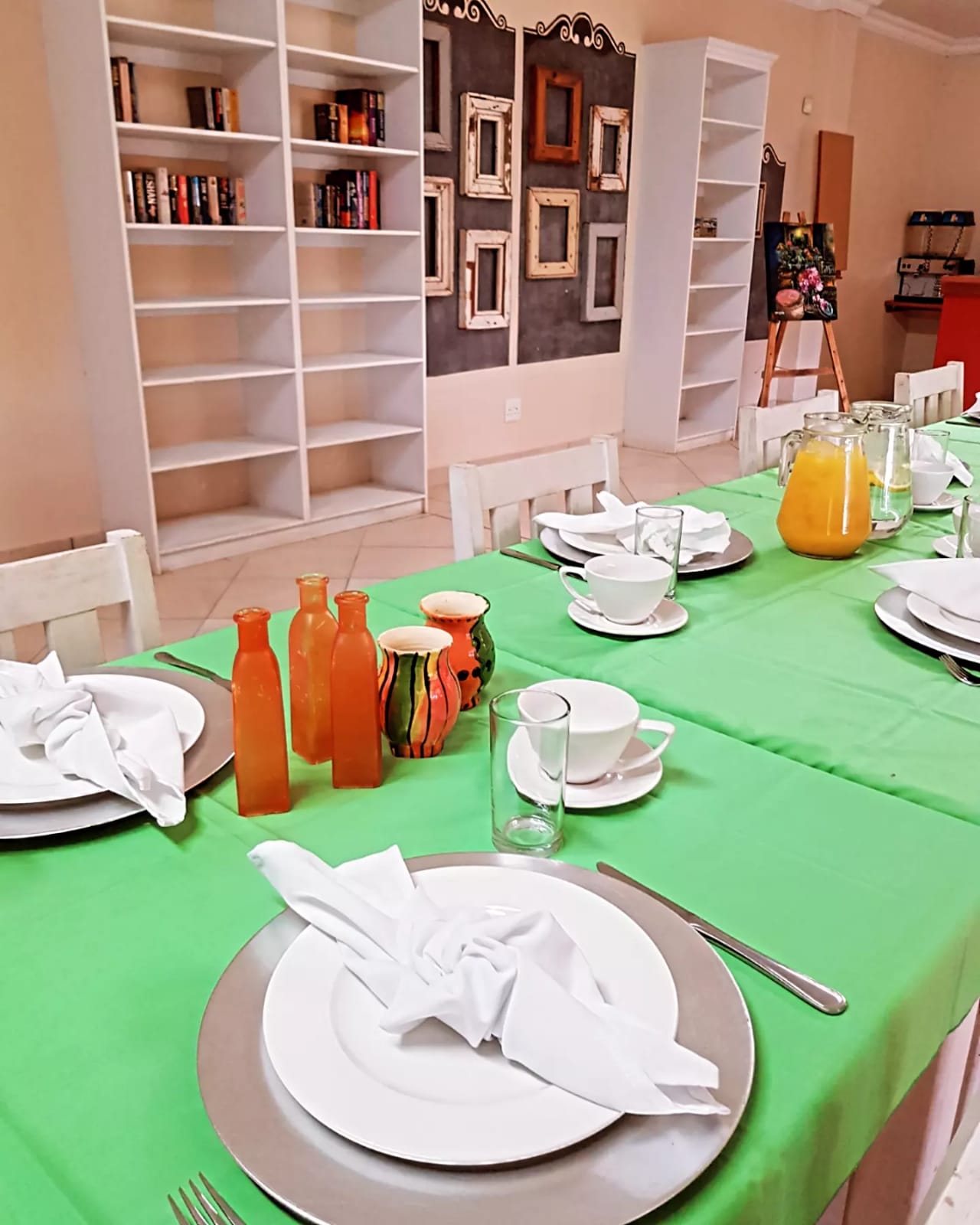 Table set with green cloth, dinnerware, and decorative bottles