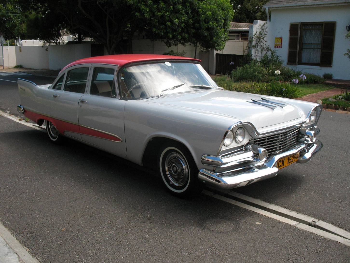 A classic vintage car with a red and silver finish parked on the street.