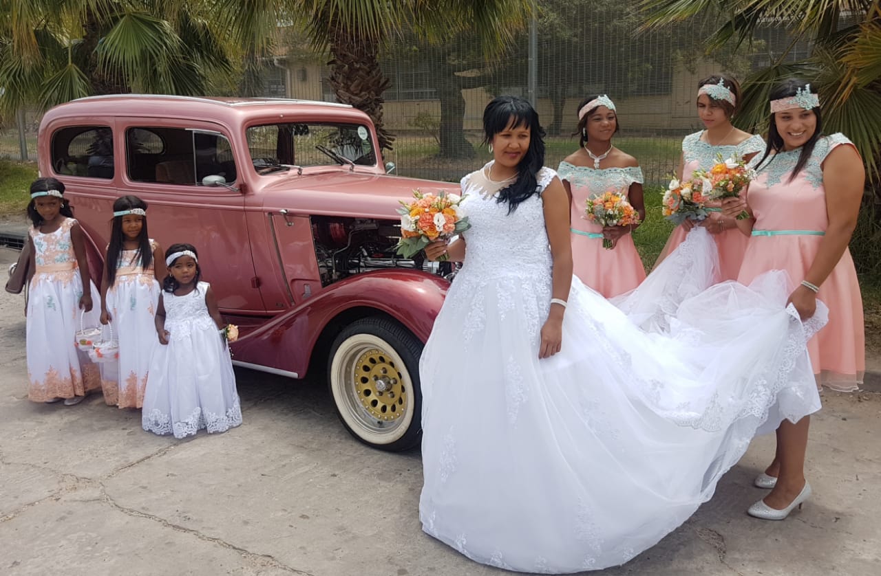 A vintage car with a bride and bridesmaids during wedding photo session.