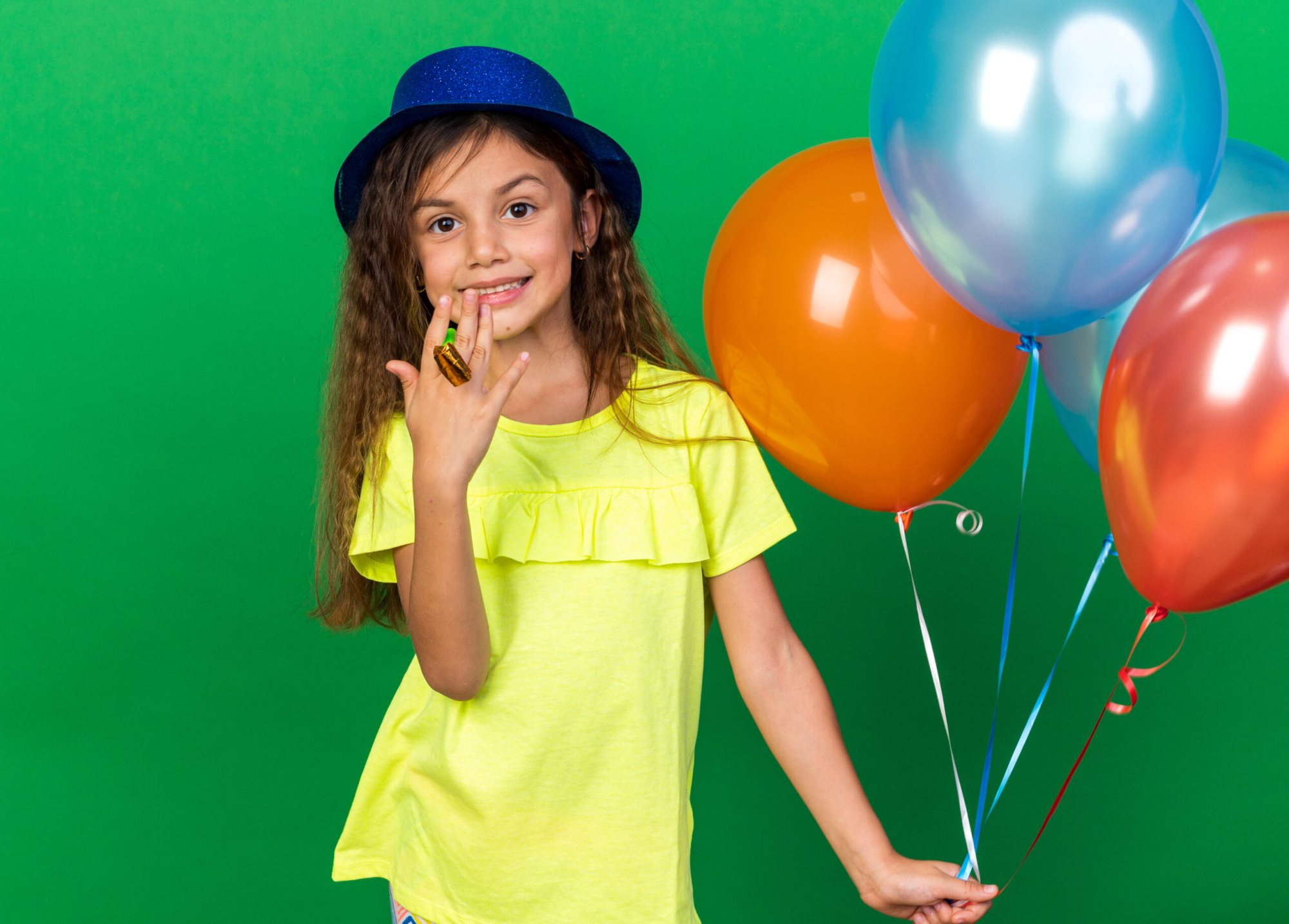 Child holding balloons, wearing a yellow shirt and blue hat
