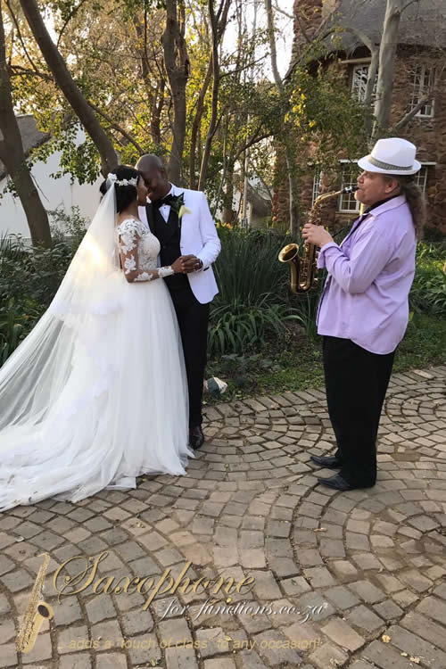 Bride and groom with saxophonist at a wedding