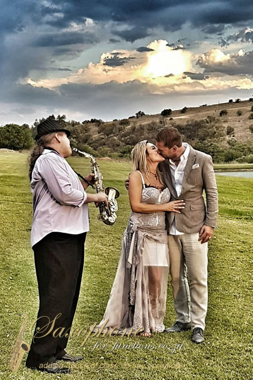 Saxophonist playing outdoors for a couple during their wedding