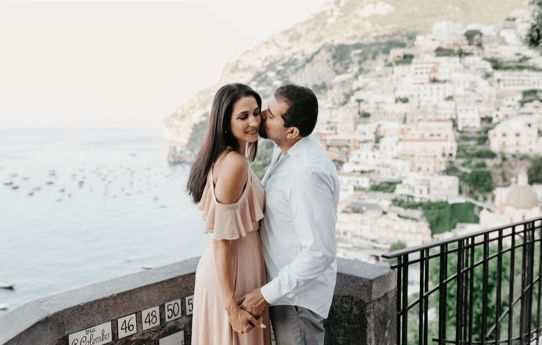 Couple sharing an intimate moment with a coastal town in the background