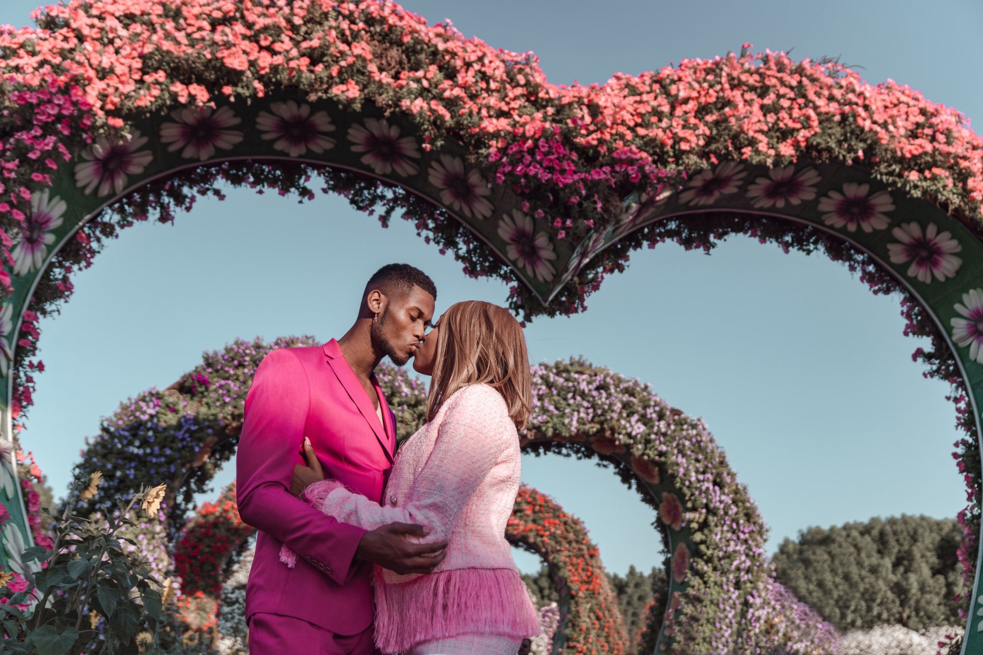 Couple kissing under floral arch in garden