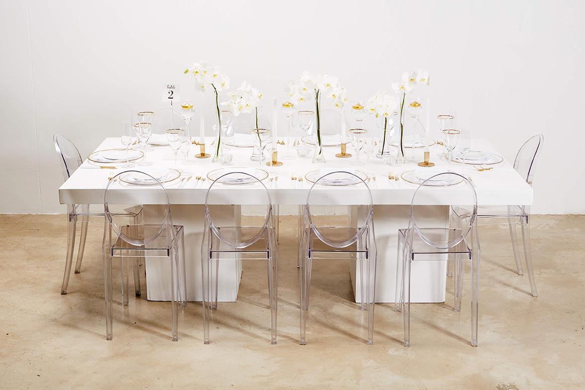 White dining table with clear chairs and floral decor