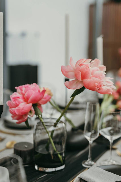 Close-up of pink peonies in glass vases on a dining table
