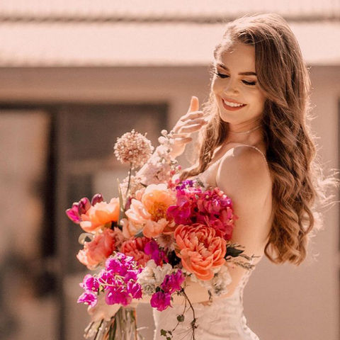 Bride holding a vibrant bouquet of peonies and flowers