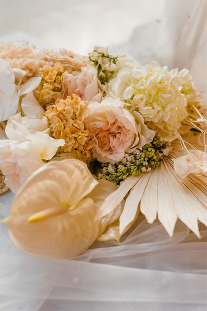 Soft floral arrangement with neutral-toned flowers and textured elements.