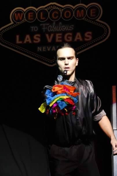 Magician performing with colorful ribbons near Las Vegas sign.