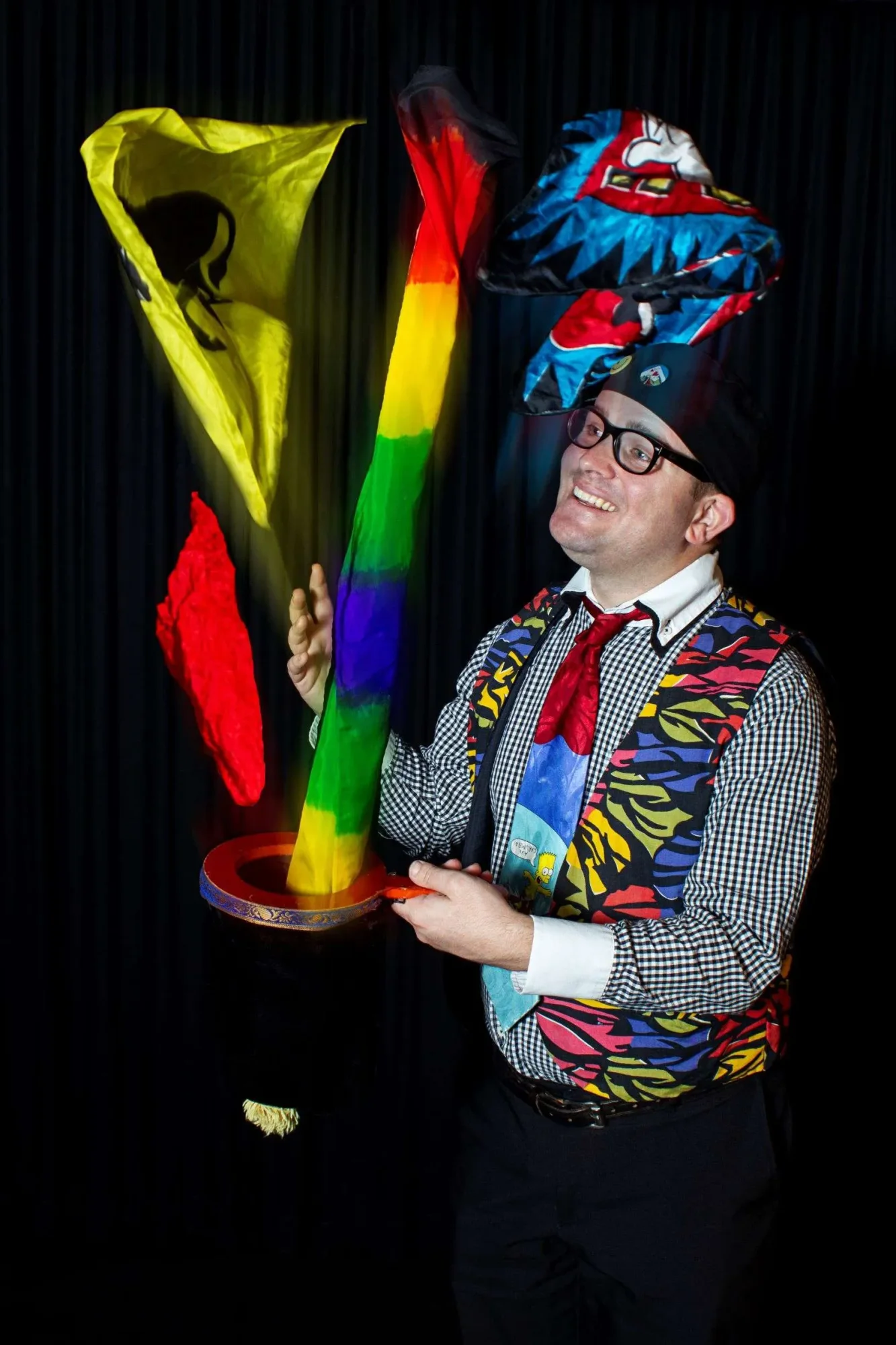 Magician performing with colorful flags and a hat