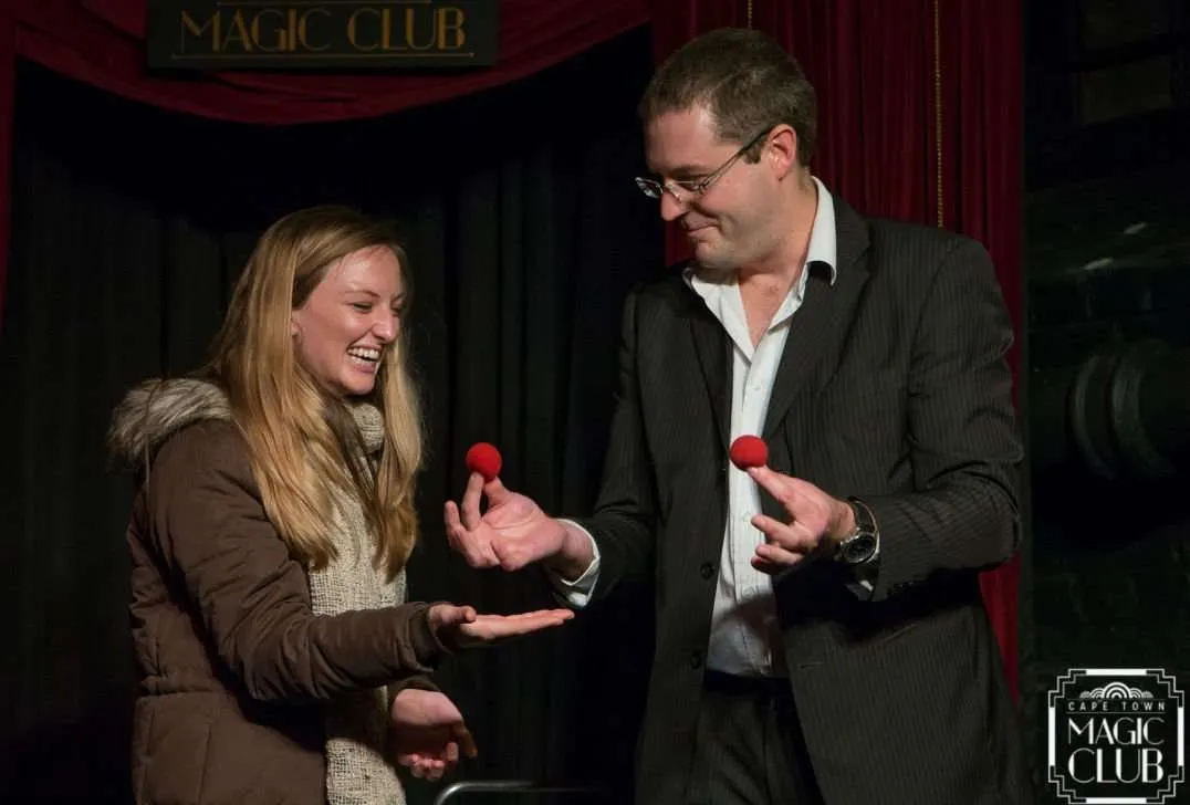 Magician performing a trick with a volunteer at Cape Town Magic Club