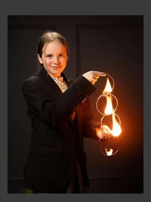 A young magician performing with flaming rings