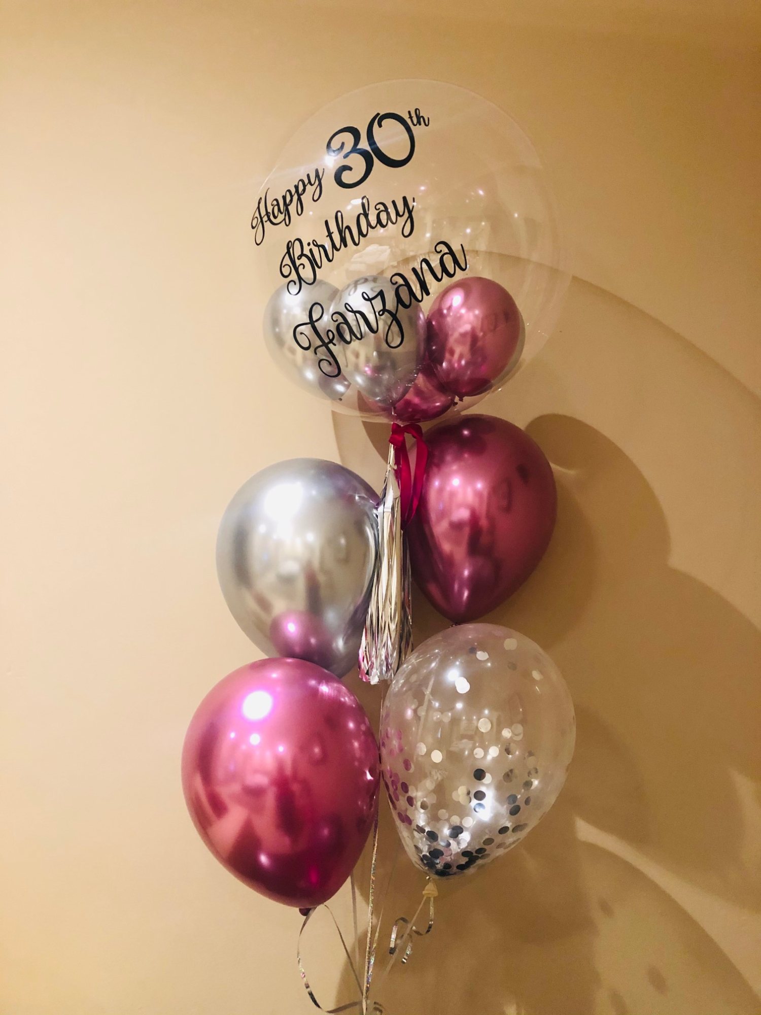 Personalised balloon bouquet for a 30th birthday with pink, silver, and clear balloons.