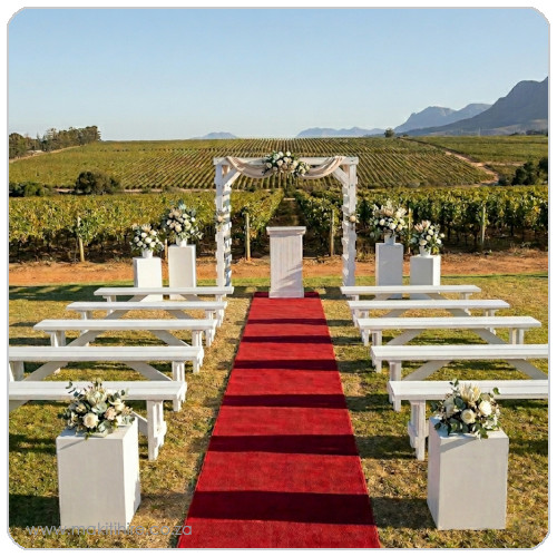 Outdoor wedding ceremony setup with red carpet and floral arrangements.