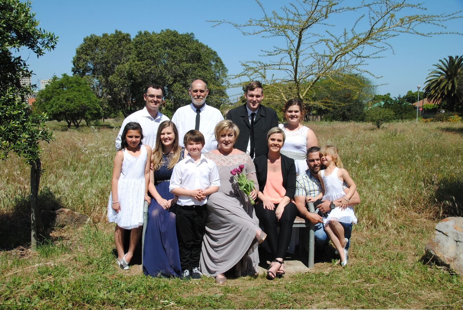 Group of people celebrating a wedding outdoors in a grassy area.