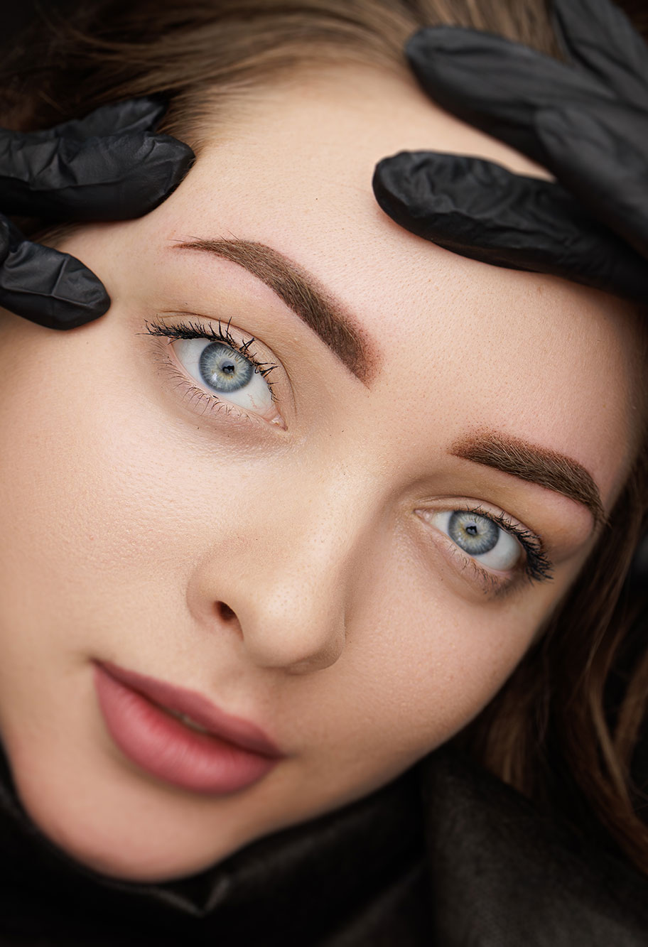 Close-up of a woman receiving brow makeup treatment.