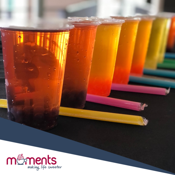 Row of colorful layered drinks with straws