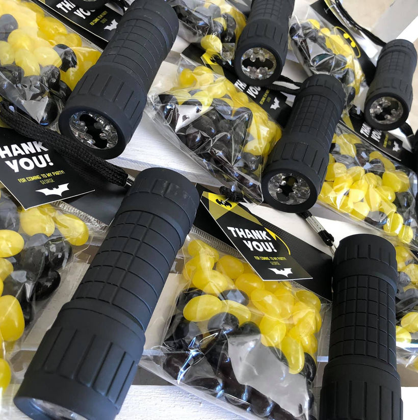 Party favor bags with black and yellow candies and flashlights