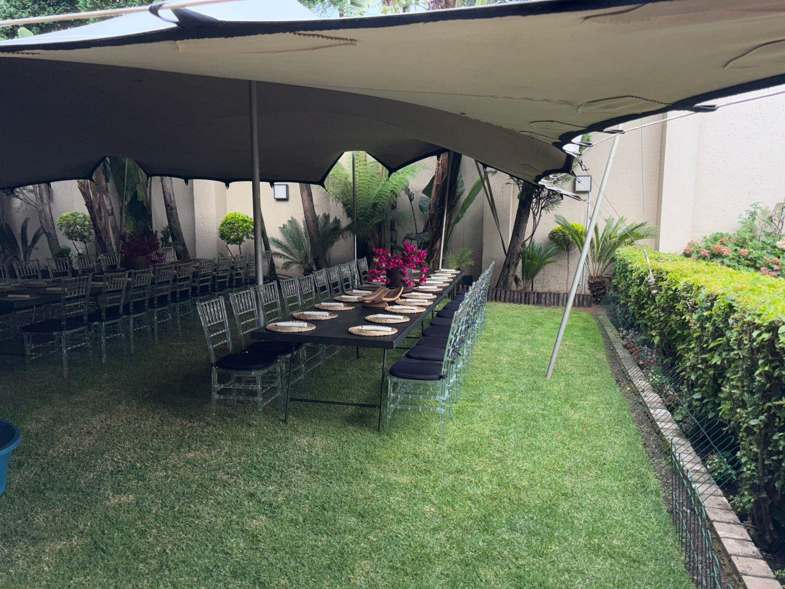 Outdoor dining area with a tent, tables, and chairs