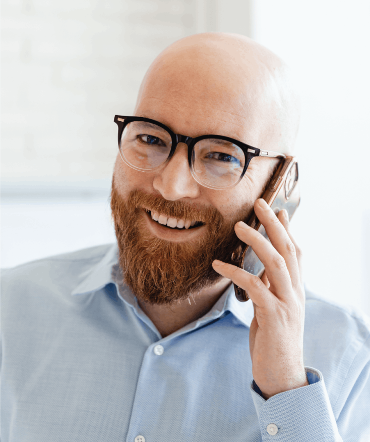 A smiling man in glasses talking on the phone