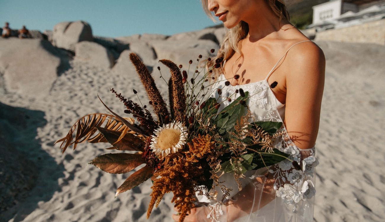 Bride holding a vibrant floral bouquet on the beach